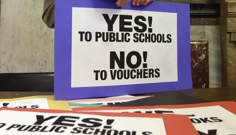 A pile of signs that say "Yes! To Public Schools. No! To Vouchers!"