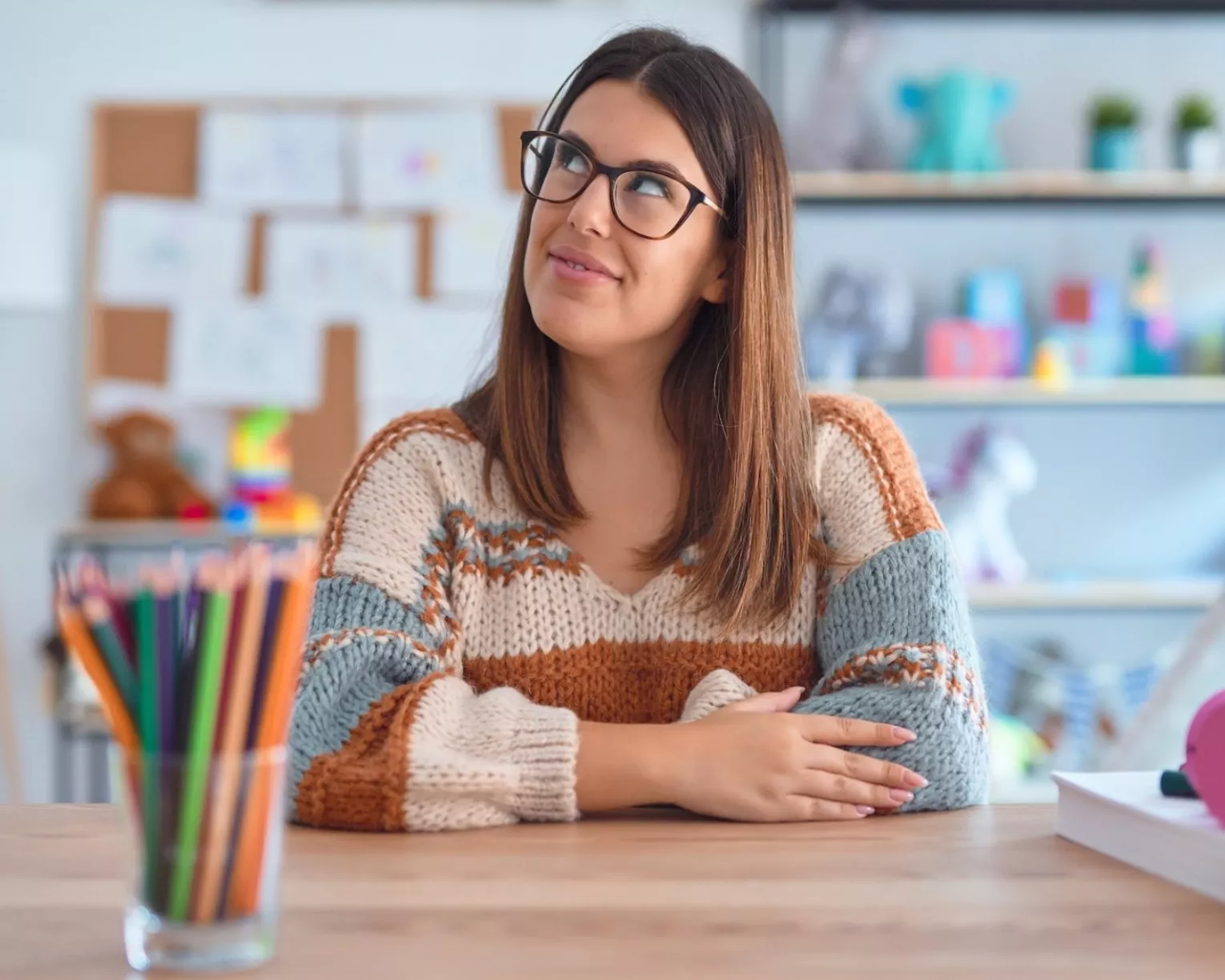An educator sits at their desk looking up thoughtfully.