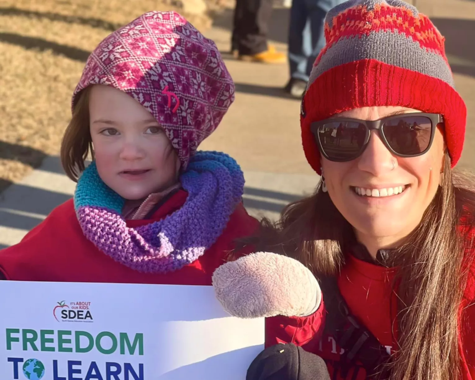 An educator and a small child smile for a camera at an advocacy event.