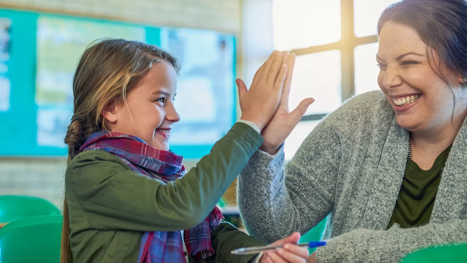An educator high-fives a student in their classroom.