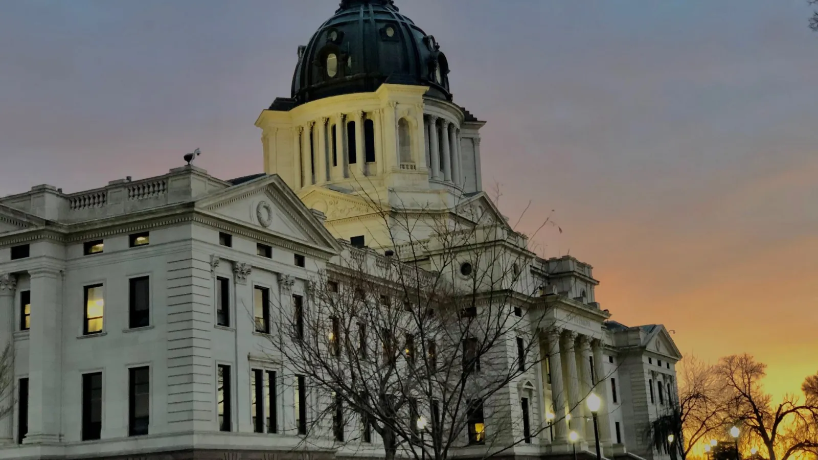 The state capitol building with a sunrise in the background.