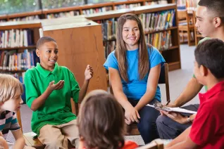 diverse students talking in a circle in school library