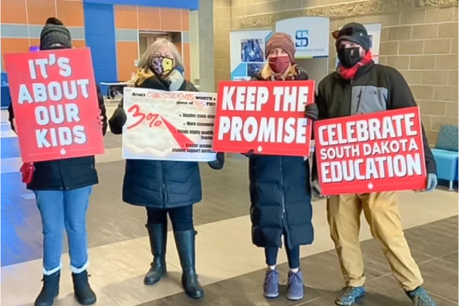 Educators with signs to "keep the promise"